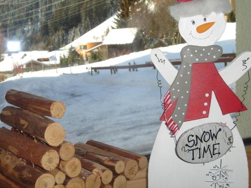 a snowman is standing next to a pile of logs at Arlenweg in Sankt Anton am Arlberg
