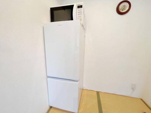 a white refrigerator in a room with a clock on the wall at 花乃郷 赤羽 in Tokyo