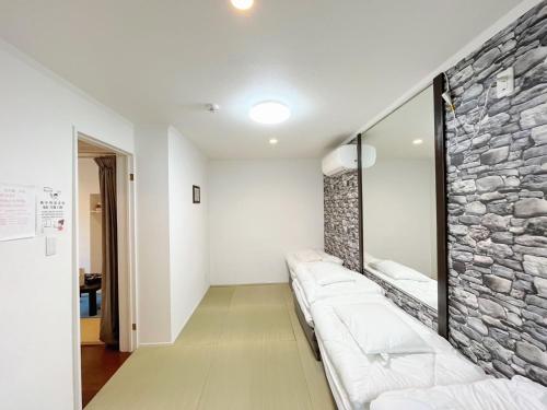 a living room with a stone wall and white furniture at 花乃郷 赤羽 in Tokyo