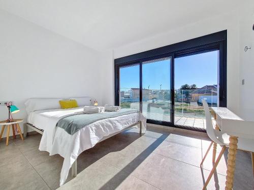 a white bedroom with a bed and a large window at San Pedro del Pinatar Villa - 5010 in San Pedro del Pinatar