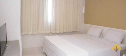 a white bedroom with a white bed and a window at Resort do LAGO - Caldas Novas in Caldas Novas