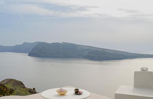 a plate with two bowls on a table next to the water at Nano Oia Villas in Oia