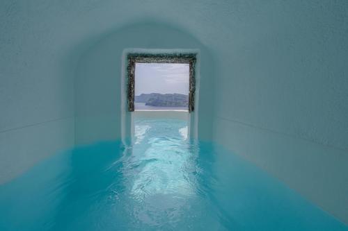 a room with a window in the water at Nano Oia Villas in Oia