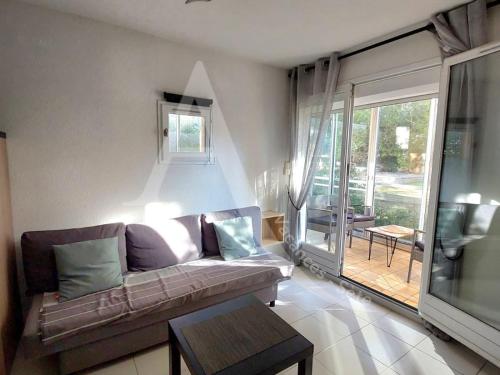 un salon avec un canapé et une grande fenêtre dans l'établissement Beau T2 moderne, residence avec piscine - Place de parking, à Sète