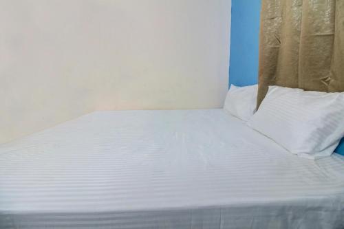 a bed with white sheets and pillows in a room at Hotel O Elite Inn in Nagpur