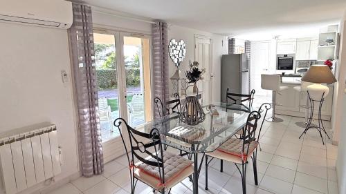 une salle à manger et une cuisine avec une table et des chaises en verre dans l'établissement Massilia 18, à Sainte-Maxime