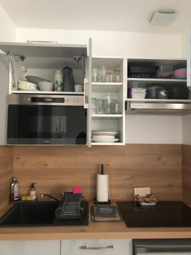 La cuisine est équipée de placards blancs et d'un four micro-ondes noir. dans l'établissement L'étape Da estrela - Cocon cosy -Vernon Giverny, à Vernon