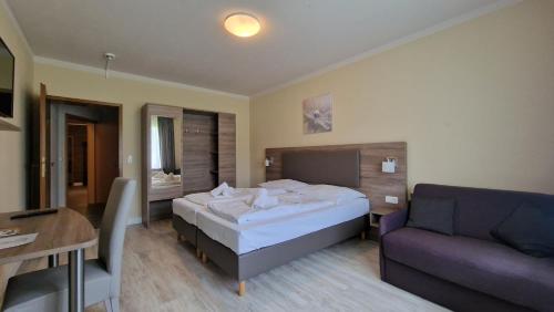 a hotel room with a bed and a couch at Hotel Tini in Bad Fallingbostel