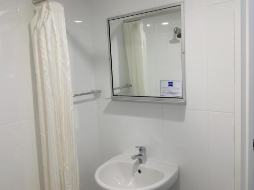 Baño blanco con lavabo y espejo en ibis Budget - Gosford en Gosford