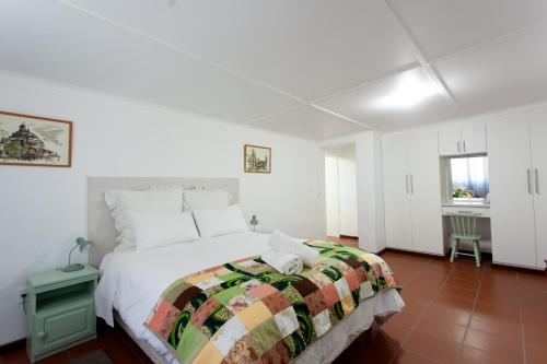 a white bedroom with a bed and a window at 4 Rothman Street B&B in Graaff-Reinet