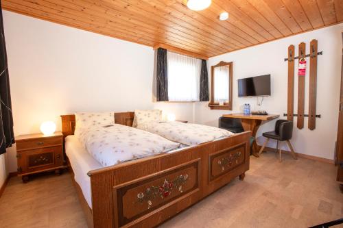 a bedroom with a bed and a desk with a computer at Hotel Restaurant Schönau in Wildhaus