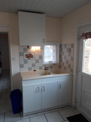 une cuisine blanche avec un évier et une fenêtre dans l'établissement La Chambre à Four, à Frampas