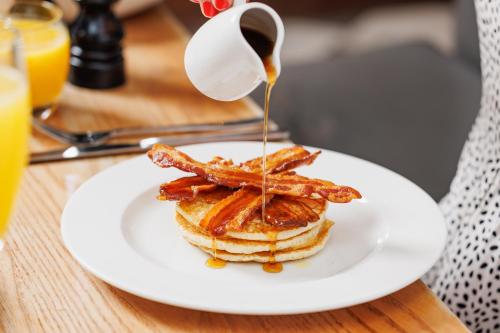 a plate of pancakes with bacon and syrup on a table at The High Field Town House in Birmingham