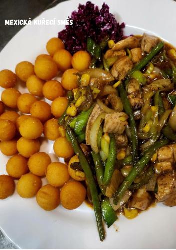a plate of food with chicken and vegetables and oranges at Penzion u Martina in Liberec