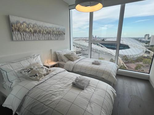 two beds in a room with a view of a stadium at The Podium 2B2B - 50mtr to ACCOR in Sydney