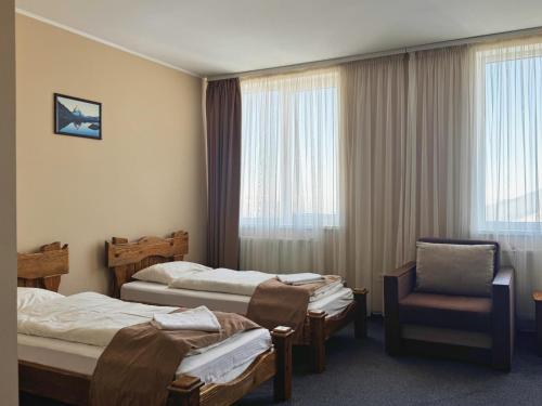a hotel room with three beds and a chair at Vershyna in Dragobrat