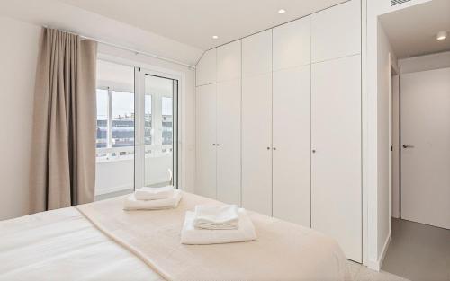 a white bedroom with a bed with two towels on it at Penthouse with Terrace near Gran Via and Camp Nou in Barcelona