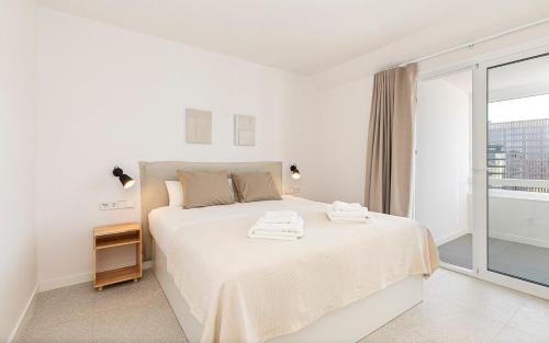 a white bedroom with a bed with two towels on it at Penthouse with Terrace near Gran Via and Camp Nou in Barcelona