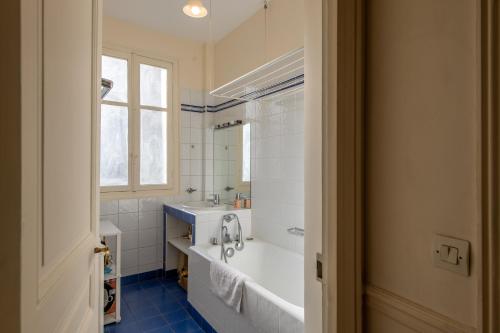 une salle de bain avec une baignoire, un lavabo et une fenêtre dans l'établissement Francisque Sarcey - Appartement proche Trocadéro, à Paris
