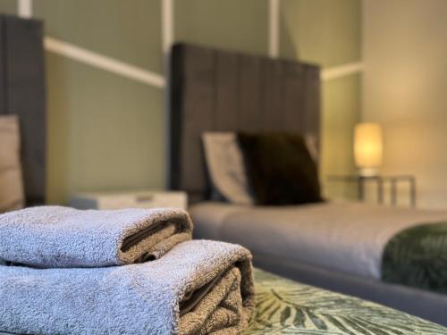 a pile of towels sitting on a table next to a bed at Modern 2 Bedroom Home In Central Location with 3 Beds and Free Driveway Parking in Doncaster