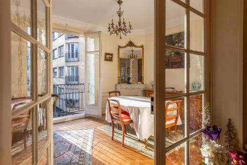 d'une salle à manger avec une table et quelques fenêtres. dans l'établissement Francisque Sarcey - Appartement proche Trocadéro, à Paris