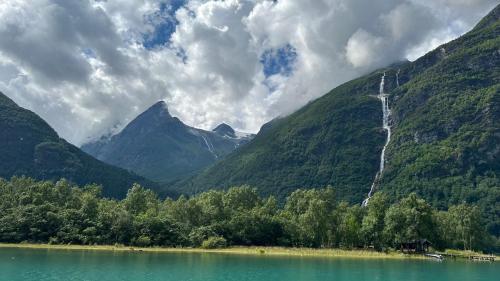 a waterfall on the side of a mountain with a lake at Solvik #apartment #Loen in Loen