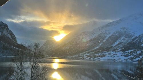 a sunset over a river with snow covered mountains at Solvik #apartment #Loen in Loen