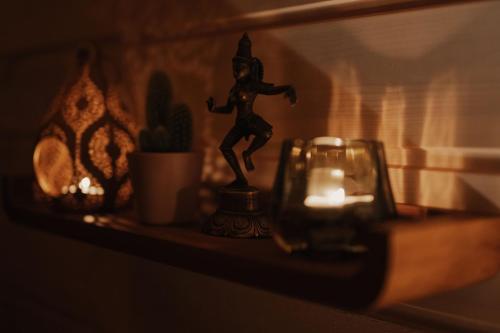 a candle and a statue of a man on a shelf at Kisvacok tiny house in Kismaros
