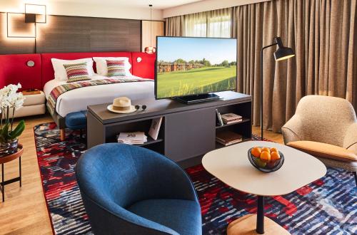 a hotel room with a bed and a tv at Cabot Hotel Bordeaux - MGallery Collection in Le Pian-Médoc