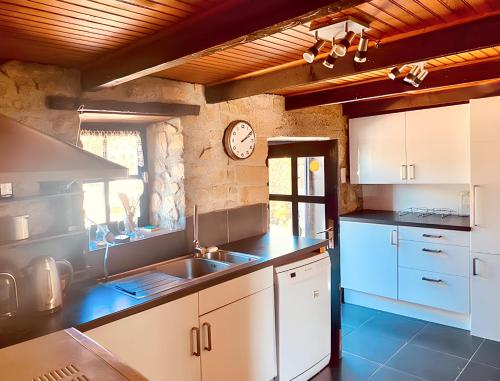 une cuisine avec un évier et une horloge murale dans l'établissement Maison accueillante à Erdeven avec jardin, à Erdeven