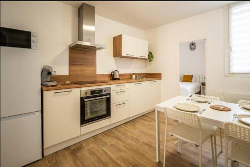 une cuisine blanche avec une table et une salle à manger dans l'établissement Au Pied des Remparts-Cité Médiévale, à Carcassonne