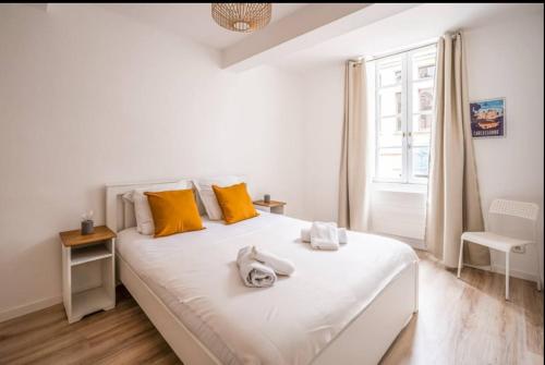 - une chambre avec un grand lit blanc et des oreillers jaunes dans l'établissement Au Pied des Remparts-Cité Médiévale, à Carcassonne