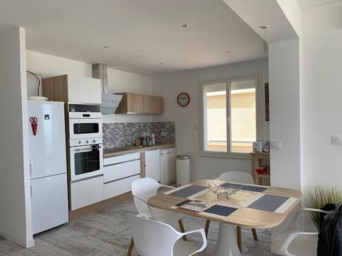une cuisine avec une table et un réfrigérateur blanc dans l'établissement Beau T3 180 degree sea view, à Palavas-les-Flots