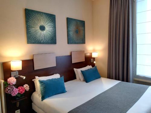 a bedroom with a large bed with blue pillows at Hôtel de Champagne in Angers