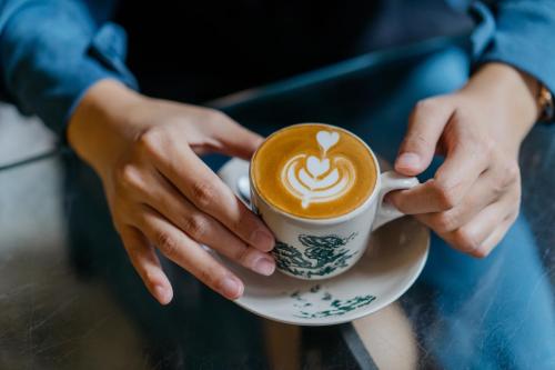 a person is holding a cup of coffee at Citadines Science City Guangzhou-Shuttle bus to Canton Fair Complex during Canton Fair period in Guangzhou