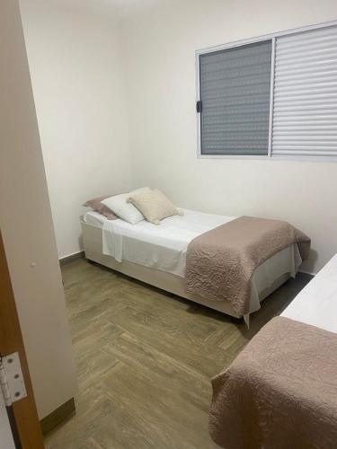 a bedroom with two beds and a window at Casa Ribeiro Aconchegante no centro de Araxá in Araxá