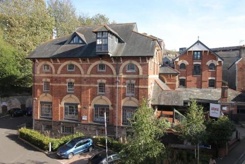 a large brick building with a car parked in front of it at 4A The Courtyard, City Centre Apartment, Exeter in Exeter