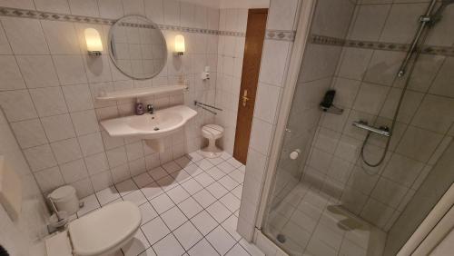 a bathroom with a shower and a toilet and a sink at Hotel Tini in Bad Fallingbostel