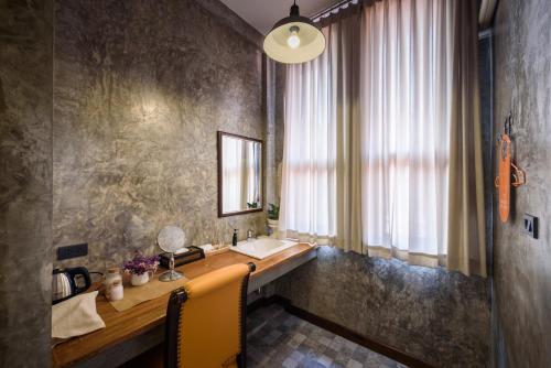 a bathroom with a vanity with a sink and a window at The Wishes Hotel at Chiangmai in Chiang Mai