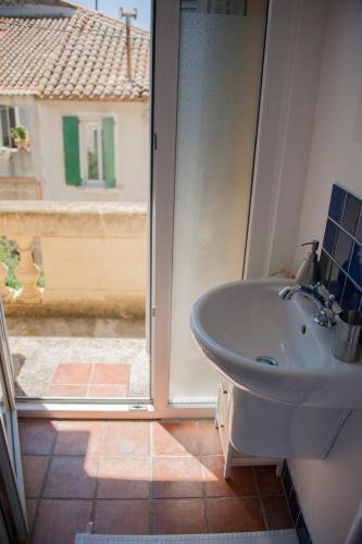 La salle de bains est pourvue d'un lavabo et d'une porte coulissante en verre. dans l'établissement Maison Pelissier Bed and Breakfast with swemming pool, à Cuxac-dʼAude