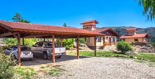 a house with two cars parked in a driveway at Aires Serranos - Suites in La Cumbrecita