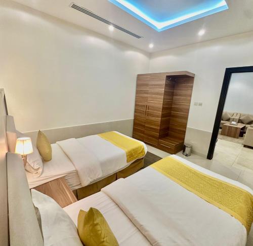 a hotel room with two beds and a mirror at توارن للشقق المخدومة الاقتصادية in Riyadh