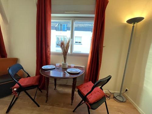 une table et des chaises dans une pièce avec une fenêtre dans l'établissement Casa Maillé, à Angers