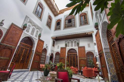 a courtyard of a mosque with red chairs and wooden doors at Riad - Dar Al Andalous in Fès
