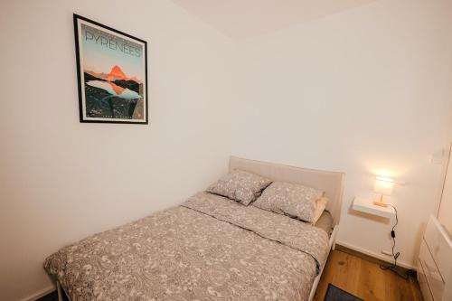 - une petite chambre avec un lit et une photo sur le mur dans l'établissement Loft travel business, à Pau