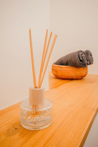un récipient en verre avec des bâtons sur une table en bois dans l'établissement Loft travel business, à Pau