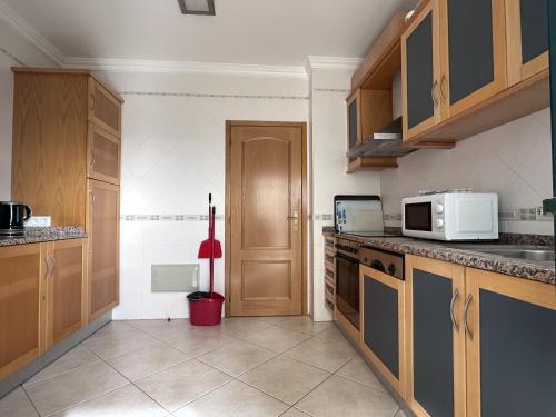 a kitchen with wooden cabinets and a white microwave at BayView Albufeira in Albufeira