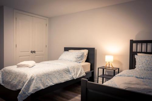 a small bedroom with two beds and a lamp at Cozy Barrie Home - Minutes to College & Hospital in Barrie