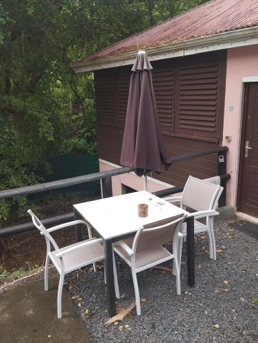 a table and two chairs and an umbrella on a patio at Bungalow et Duplex de Island Bay in Bouillante