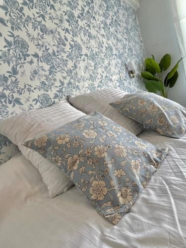 - un lit avec des oreillers et du papier peint bleu et blanc dans l'établissement La Loge de Gustave et son patio avec Wifi et parking privée, à Mont-de-Marsan